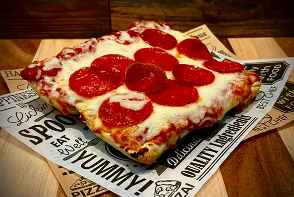 Square pepperoni pizza on decorative paper.