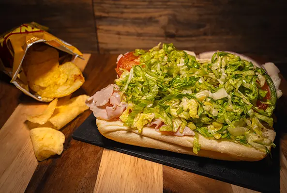 Sub sandwich with chips on wooden table.