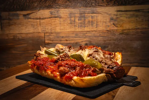 Italian beef sandwich with peppers on board.