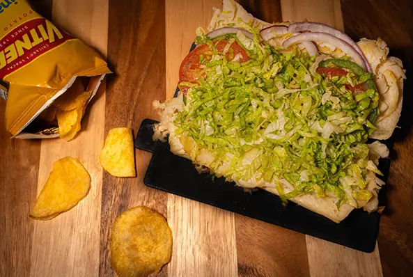 Sub sandwich with chips on wooden table.