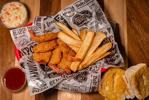 Fried shrimp, fries, coleslaw, and bread rolls.