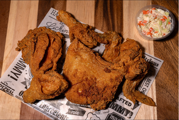 Fried chicken with coleslaw on wooden table.