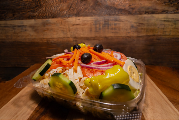 A salad with vegetables in a plastic container.