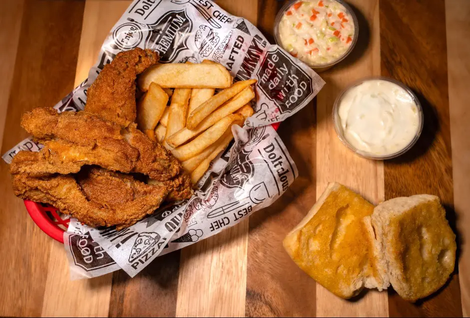 Fried fish, fries, coleslaw, tartar sauce, bread.