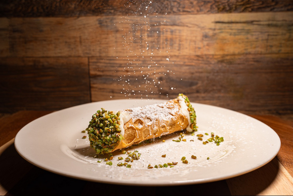 Cannoli with powdered sugar and pistachios.